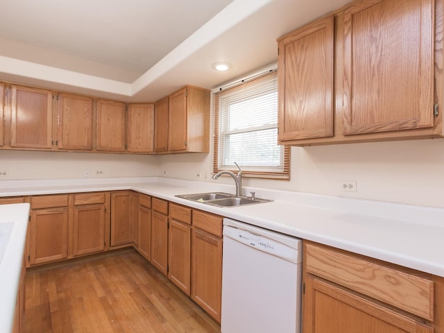 kitchen with dishwasher, a sink, light countertops, and light wood-type flooring