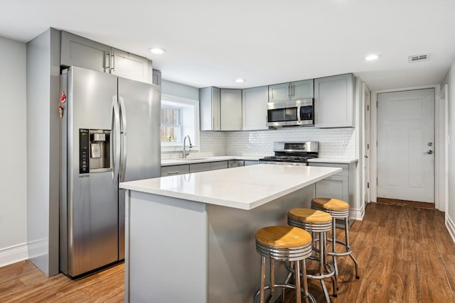 4825 W Ainslie St, Chicago, IL 60630 - kitchen with appliances with stainless steel finishes, gray cabinetry, dark wood-type flooring, light countertops, and a kitchen island