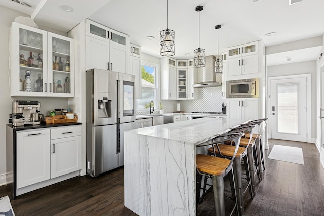 4825 W Ainslie St, Chicago, IL 60630 - kitchen with appliances with stainless steel finishes, wall chimney exhaust hood, dark wood finished floors, light stone countertops, and a kitchen island