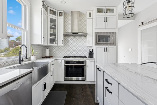 4825 W Ainslie St, Chicago, IL 60630 - kitchen featuring stainless steel appliances, wall chimney exhaust hood, dark wood-style flooring, decorative backsplash, and a barn door