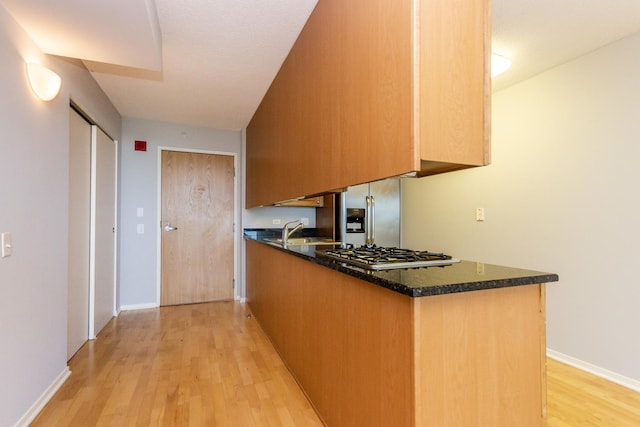 9715 Woods Dr Unit 805, Skokie, IL 60077 - kitchen with stainless steel appliances, light wood-style flooring, a sink, dark stone counters, and a peninsula