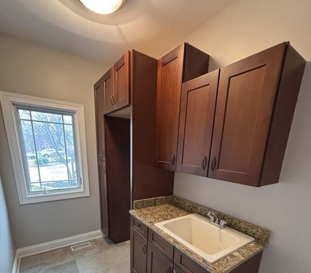 interior space featuring baseboards, visible vents, and a sink
