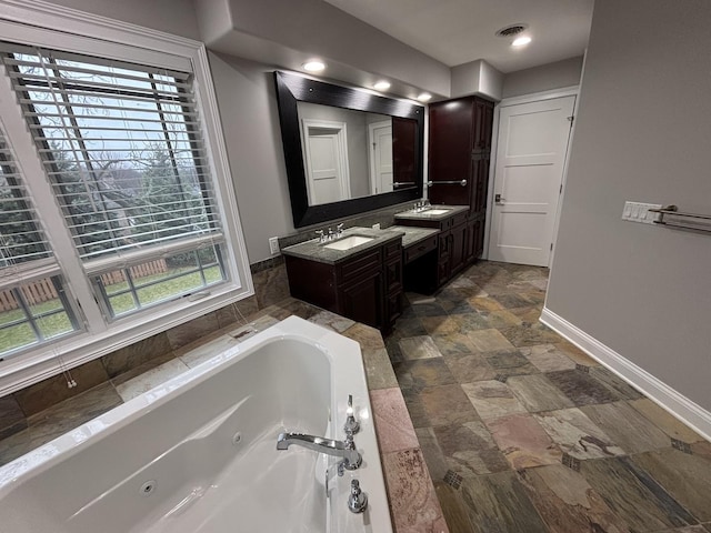 full bathroom featuring a whirlpool tub, visible vents, vanity, stone finish flooring, and baseboards