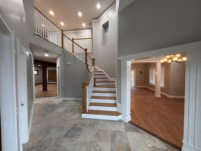 stairway with stone finish flooring, baseboards, a towering ceiling, and decorative columns