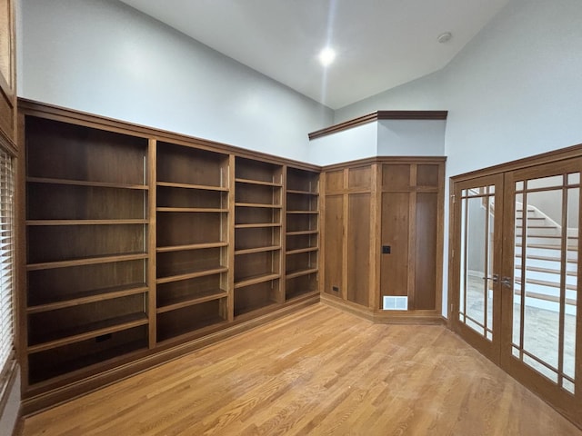 empty room featuring high vaulted ceiling, french doors, visible vents, and light wood-style flooring