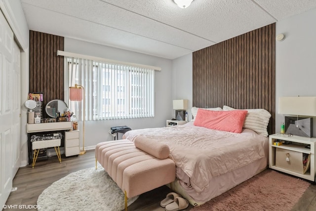 bedroom with a textured ceiling, baseboards, and wood finished floors
