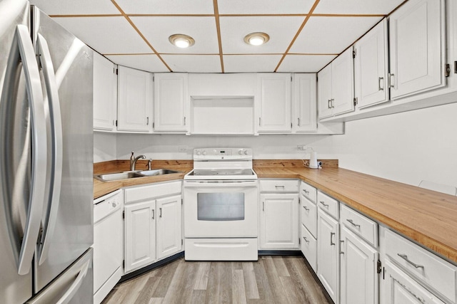 kitchen with white cabinetry, light wood finished floors, a sink, and white appliances