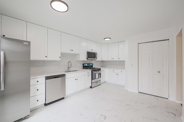 kitchen featuring white cabinets, marble finish floor, stainless steel appliances, light countertops, and a sink