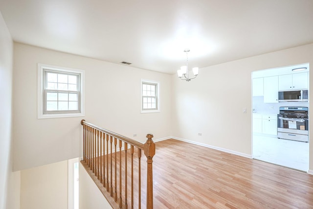 interior space featuring a healthy amount of sunlight, an inviting chandelier, visible vents, and wood finished floors