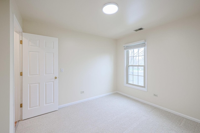 spare room with visible vents, baseboards, and light carpet