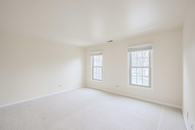 empty room with visible vents, light carpet, and baseboards