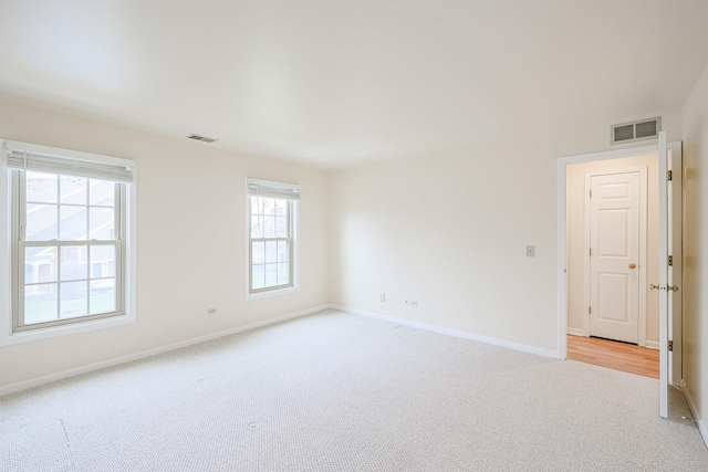 spare room with light colored carpet, baseboards, and visible vents