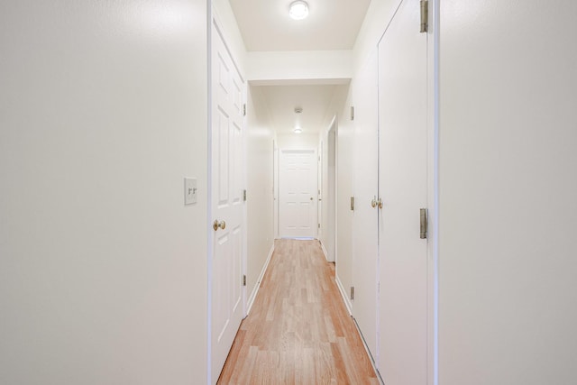 hall featuring baseboards and light wood-style flooring