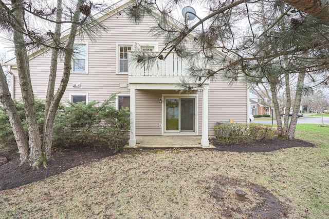 rear view of property featuring a lawn and a balcony