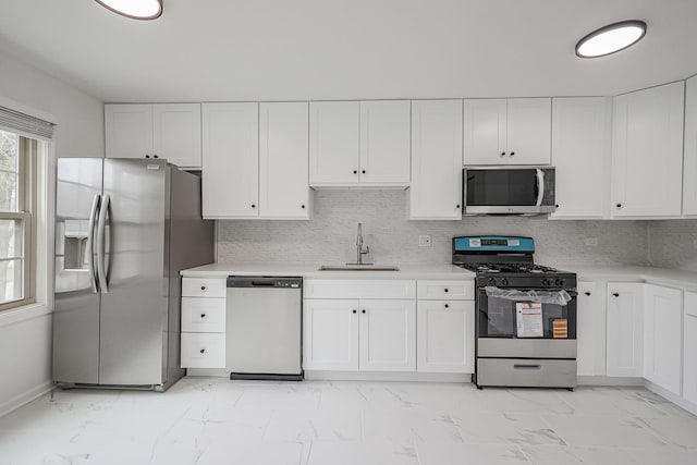 kitchen with a sink, light countertops, marble finish floor, and stainless steel appliances