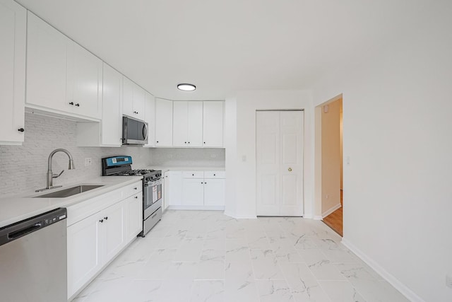 kitchen with baseboards, light countertops, stainless steel appliances, marble finish floor, and a sink
