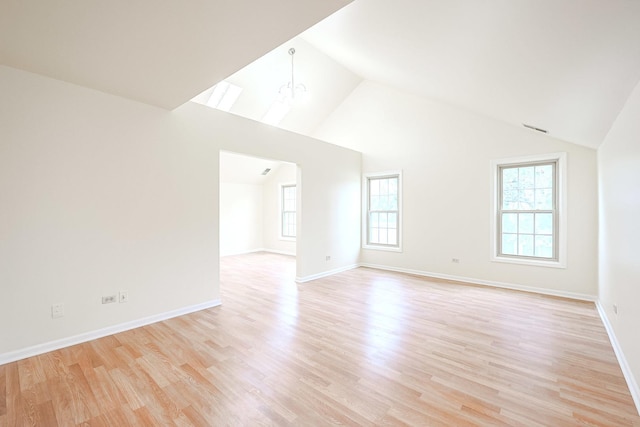 spare room featuring baseboards, light wood finished floors, high vaulted ceiling, and an inviting chandelier