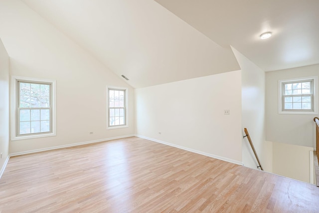 unfurnished room featuring plenty of natural light, light wood-type flooring, and vaulted ceiling