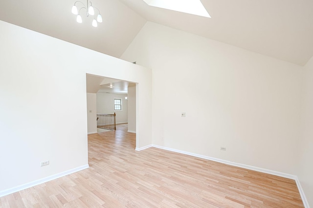 spare room featuring light wood-type flooring, a skylight, and baseboards