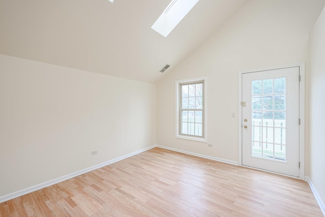 unfurnished room with visible vents, light wood-style flooring, lofted ceiling with skylight, and baseboards