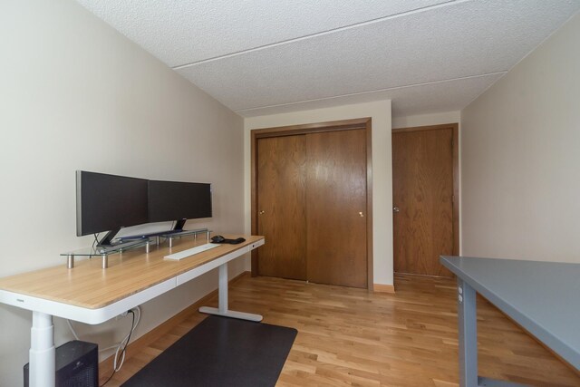 home office featuring baseboards, a textured ceiling, and light wood-style flooring