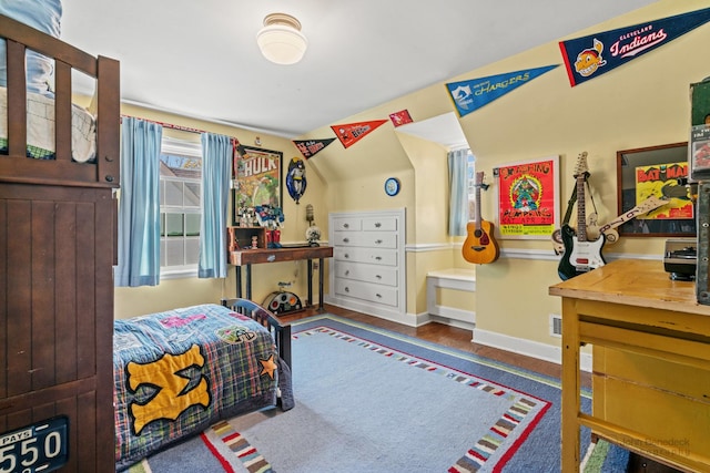 bedroom featuring baseboards, wood finished floors, and vaulted ceiling