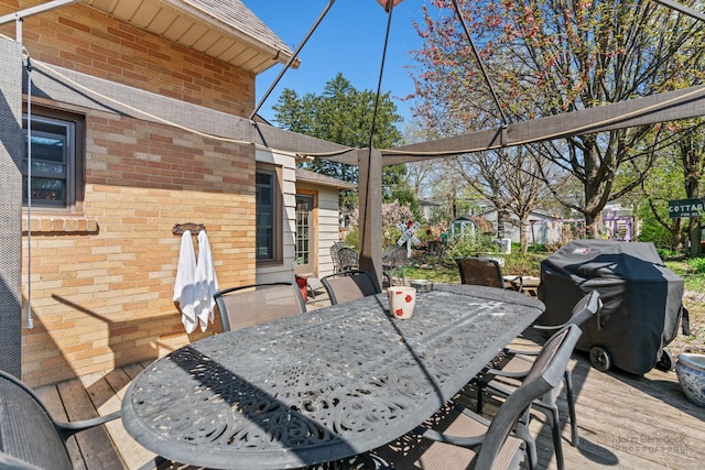 wooden terrace with a grill and outdoor dining space