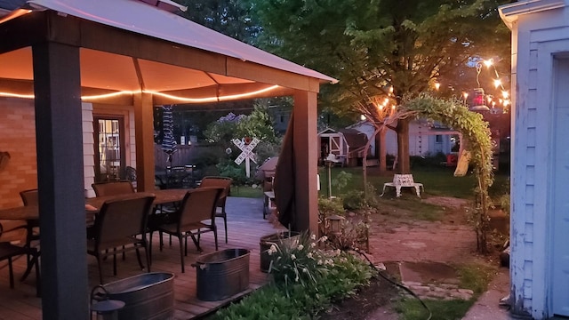 patio at twilight featuring a deck and outdoor dining area