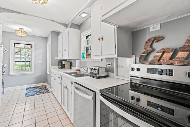 kitchen with stainless steel appliances, arched walkways, light countertops, and a sink