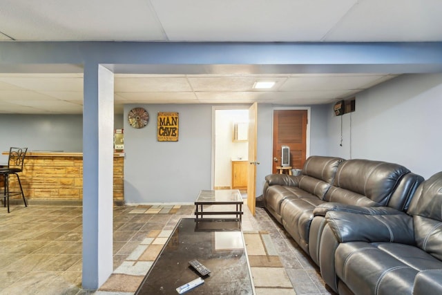 living area with stone finish floor and a drop ceiling