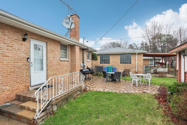 rear view of house featuring a chimney, fence, a yard, a patio, and brick siding