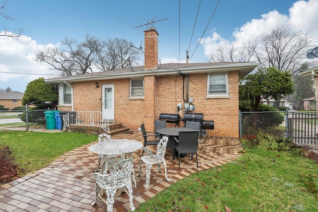 rear view of house with a patio area, a chimney, fence private yard, a yard, and brick siding