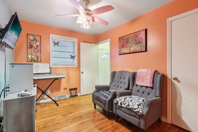 sitting room featuring baseboards, a ceiling fan, and wood finished floors