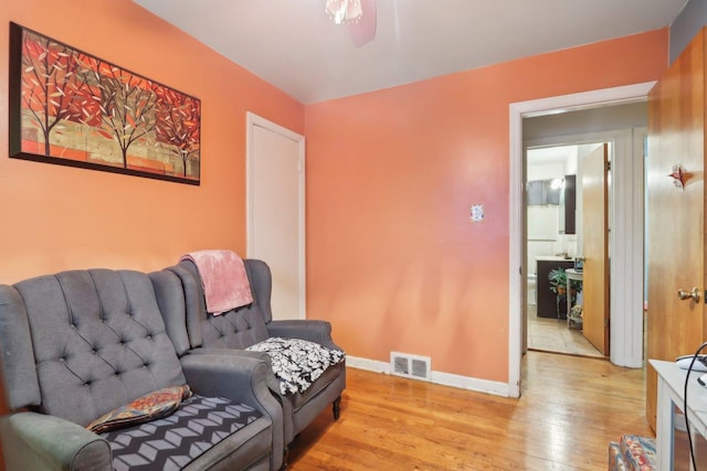 living area with light wood-style flooring, visible vents, and baseboards