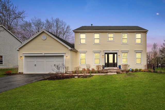 colonial home with a lawn, driveway, and an attached garage