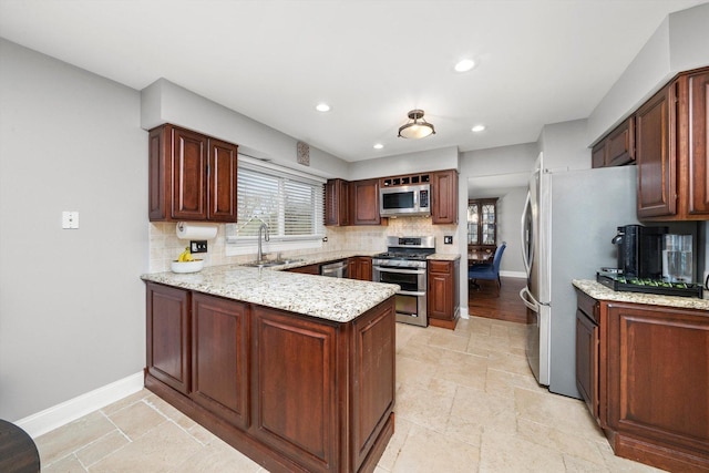 kitchen featuring tasteful backsplash, plenty of natural light, appliances with stainless steel finishes, a sink, and a peninsula