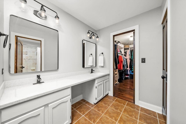 full bathroom featuring a walk in closet, tile patterned flooring, double vanity, and a sink