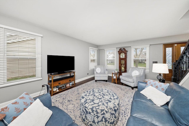 living area featuring baseboards, wood finished floors, and stairs