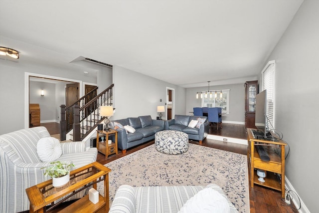 living area with a chandelier, baseboards, dark wood finished floors, and stairs