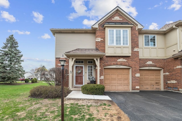 townhome / multi-family property with brick siding, an attached garage, a front lawn, and aphalt driveway