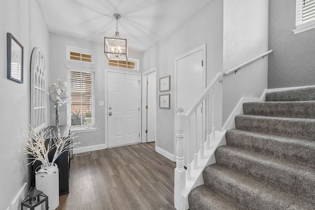 foyer with a chandelier, baseboards, wood finished floors, and stairs