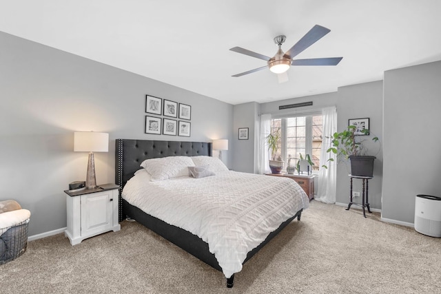 bedroom featuring light colored carpet, baseboards, and a ceiling fan