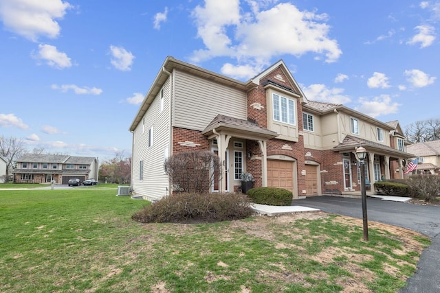 view of front facade featuring central air condition unit, a front lawn, driveway, a garage, and brick siding