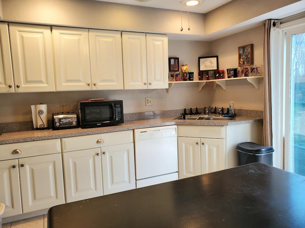 kitchen featuring white cabinets, white dishwasher, black microwave, and a sink