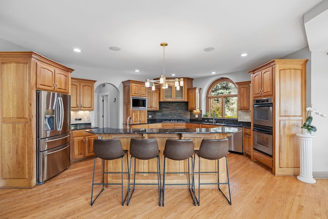 kitchen featuring appliances with stainless steel finishes, light wood-type flooring, a kitchen breakfast bar, decorative backsplash, and recessed lighting