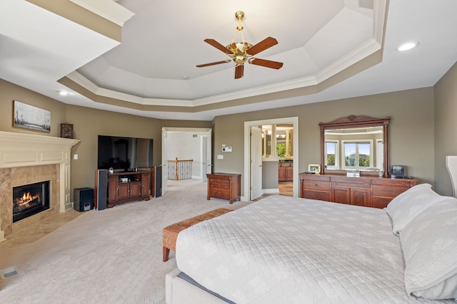 bedroom featuring a raised ceiling, crown molding, light carpet, a premium fireplace, and recessed lighting