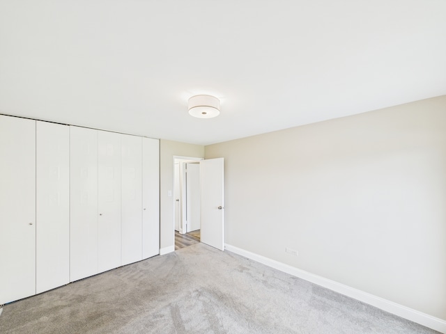 unfurnished bedroom with baseboards, carpet floors, and a closet