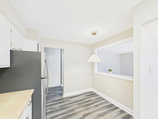 kitchen with light wood finished floors, light countertops, baseboards, white cabinets, and freestanding refrigerator