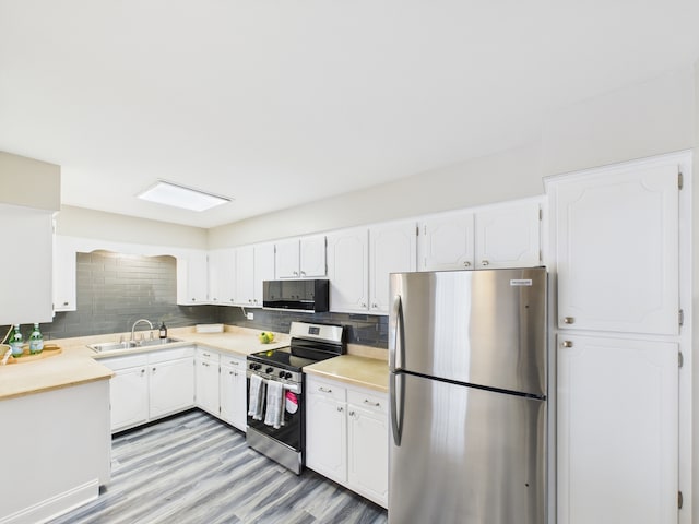 kitchen with a sink, white cabinetry, stainless steel appliances, and tasteful backsplash