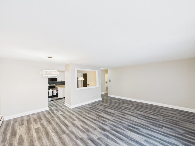 unfurnished living room with wood finished floors and baseboards